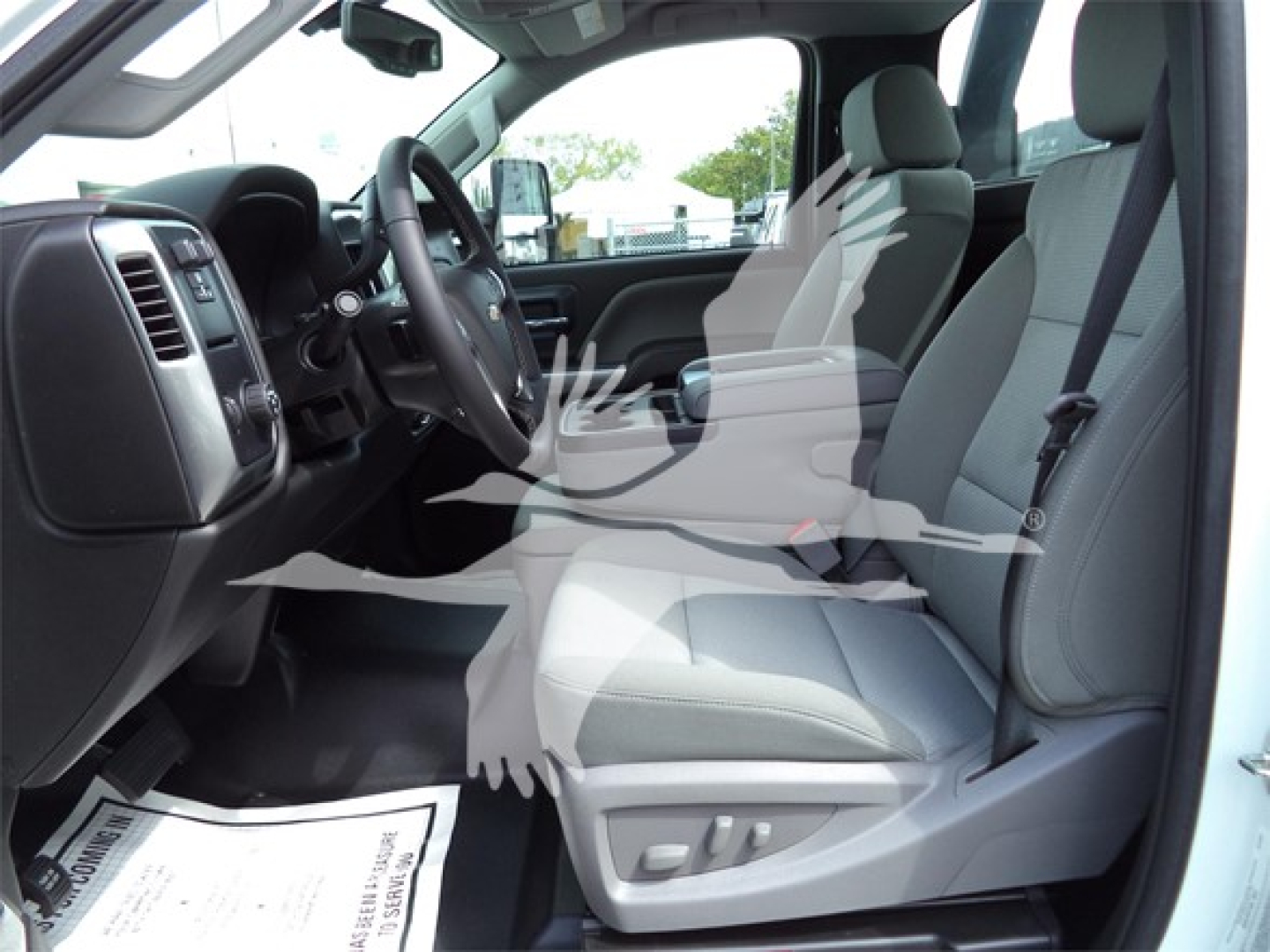 Chevrolet Silverado 6500HD interior front seats and dashboard view with grey cloth seats, steering wheel, and center console from the driver’s side.