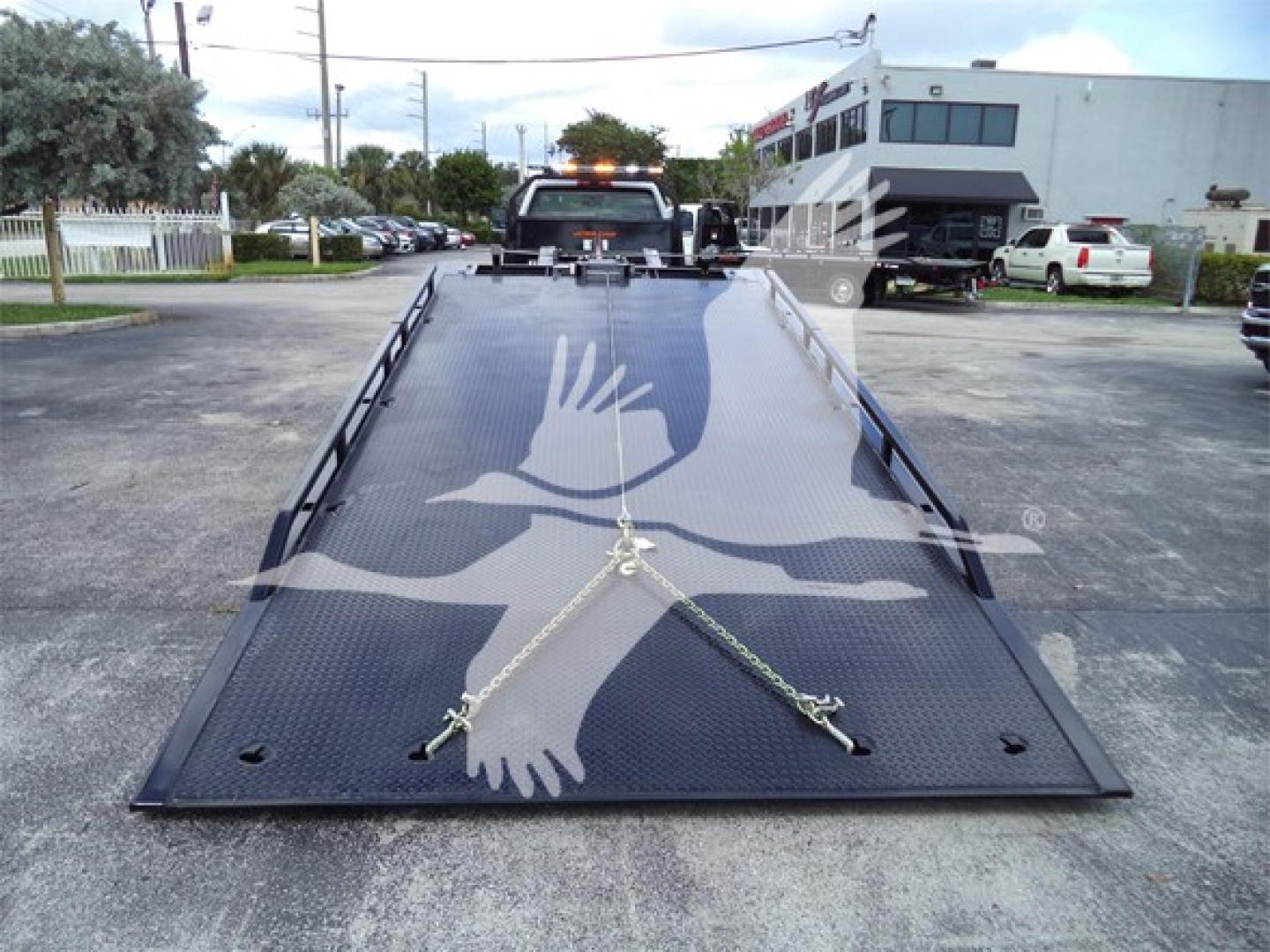 Overview of a 2023 Chevrolet Silverado 6500HD rollback truck with a black steel flatbed, loading ramps folded down, stock number J68760, VIN 1HTKHPVM9PH768760.