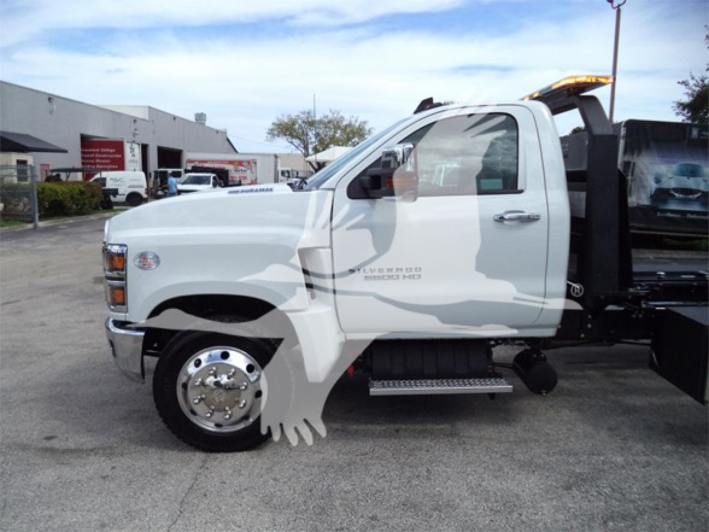 Sheet metal side view of a white 2023 Chevrolet Silverado 6500HD rollback truck with black equipment in rear and chrome wheel; no visible text legible on the cab panels.