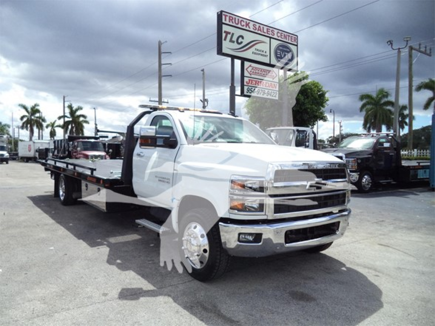 Chevrolet Silverado 6500HD rollback tow truck in dealership lot showing flatbed and front grille with chrome bumper