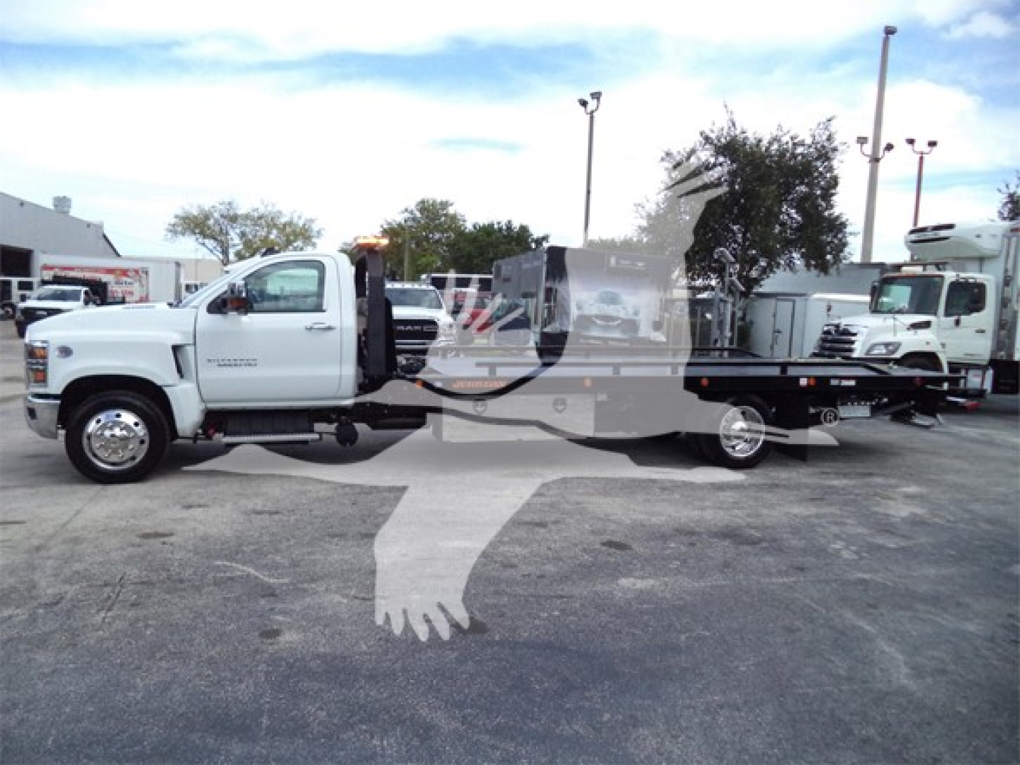 Truck chassis showing rollback wrecker body on a white Chevrolet Silverado 6500hd with flatbed/rollback equipment.