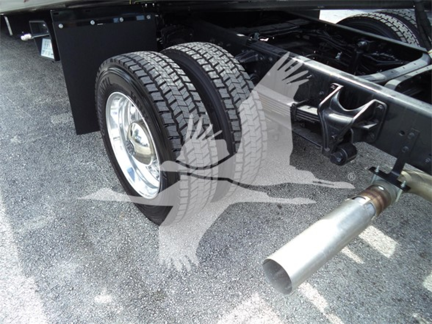 Truck wheel and dual rear tires with exhaust pipe visible under chassis in a Silverado roll-back cab chassis.
