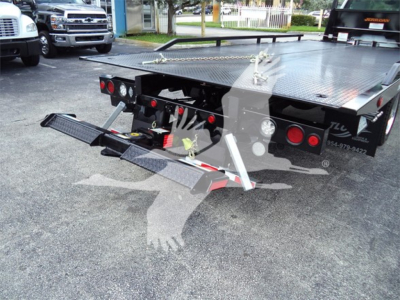 Truck bed equipped with hydraulic ramps and towing components, rear view of a 2023 Chevrolet Silverado 6500HD rollback case showing flatbed with folding ramps and taillights.