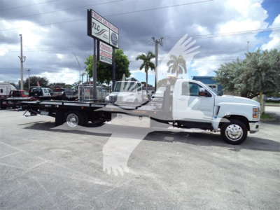 Flatbed tow truck side view showing long deck and white cab with black frame; Chevrolet Silverado 6500hd branding not visible in text