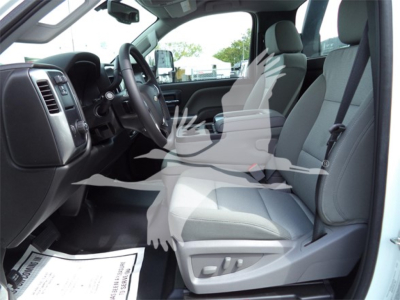 Chevrolet Silverado 6500HD interior front seats and dashboard view with grey cloth seats, steering wheel, and center console from the driver’s side.