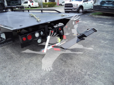 Truck rollback bed rear showing hydraulic lines, taillights, platform with diamond plate, and folding ramp in view.