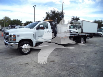 Chevrolet Silverado 6500HD rollback tow truck in white, side view with flatbed and crane in background.
