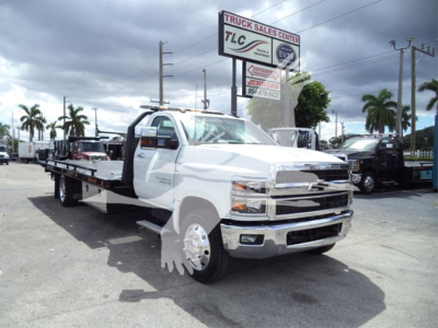 Chevrolet Silverado 6500HD rollback tow truck in dealership lot showing flatbed and front grille with chrome bumper
