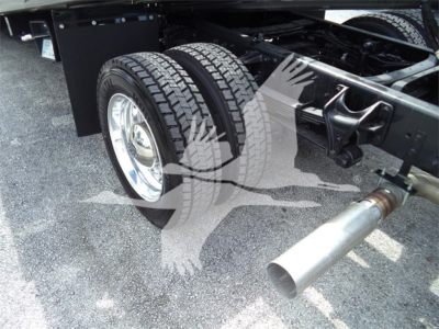 Truck wheel and dual rear tires with exhaust pipe visible under chassis in a Silverado roll-back cab chassis.
