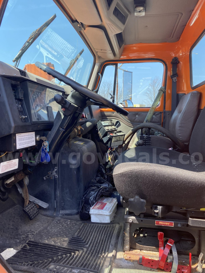 Cab interior of a 2002 International 2574 truck showing steering wheel, dashboard, seat, pedals, and control levers.