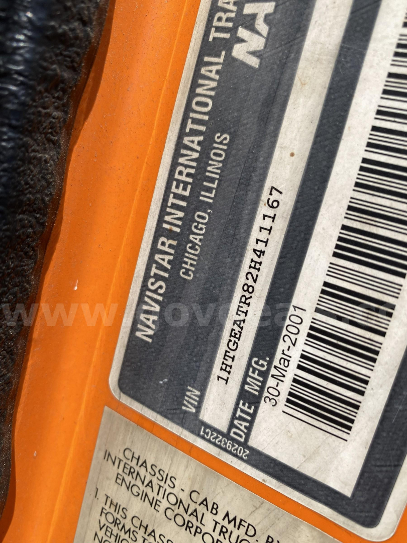 Label sticker on International truck showing VIN 1HTGEATR82H411167, manufacturing date 30-Mar-2001, NAS International chassis info, and barcode. Orange frame around label.