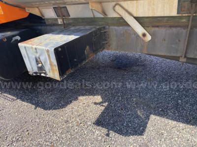 Truck underwater view showing metal toolbox mounted under the frame of a 2002 International 2574, rusted edges, gravel surface.