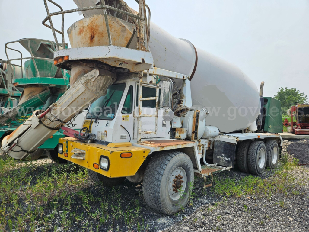 Concrete mixer truck with cement mixer barrel and chute; front bumper area shows yellow guard; multiple tires; some rust on metal components; no legible serials or brand text visible in this view.