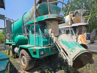Mixer truck by Oshkosh S2346 with cement chute and drum, green body, front cab, visible wear and rust on metal components.