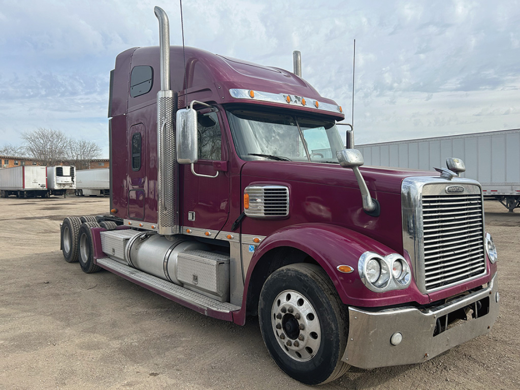 Freightliner Coronado tractor in maroon showing chrome grille and sleeper cab with dual exhaust stacks.