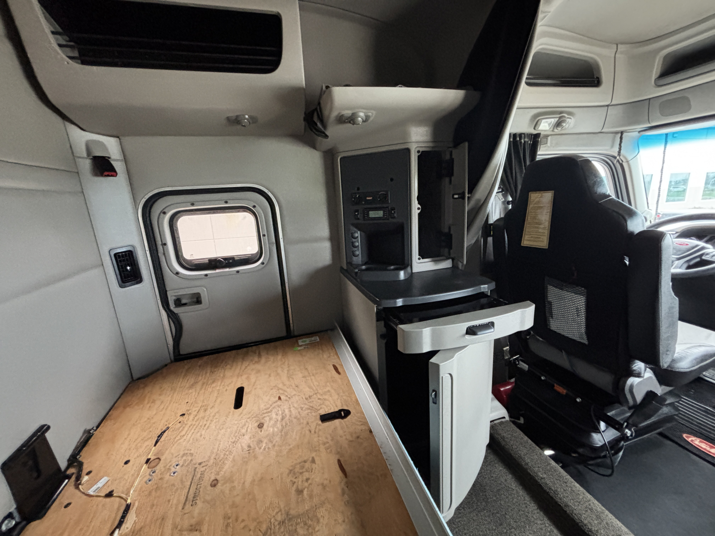 Interior of a 2020 Peterbilt 579 truck cab showing side console with storage and seating area.