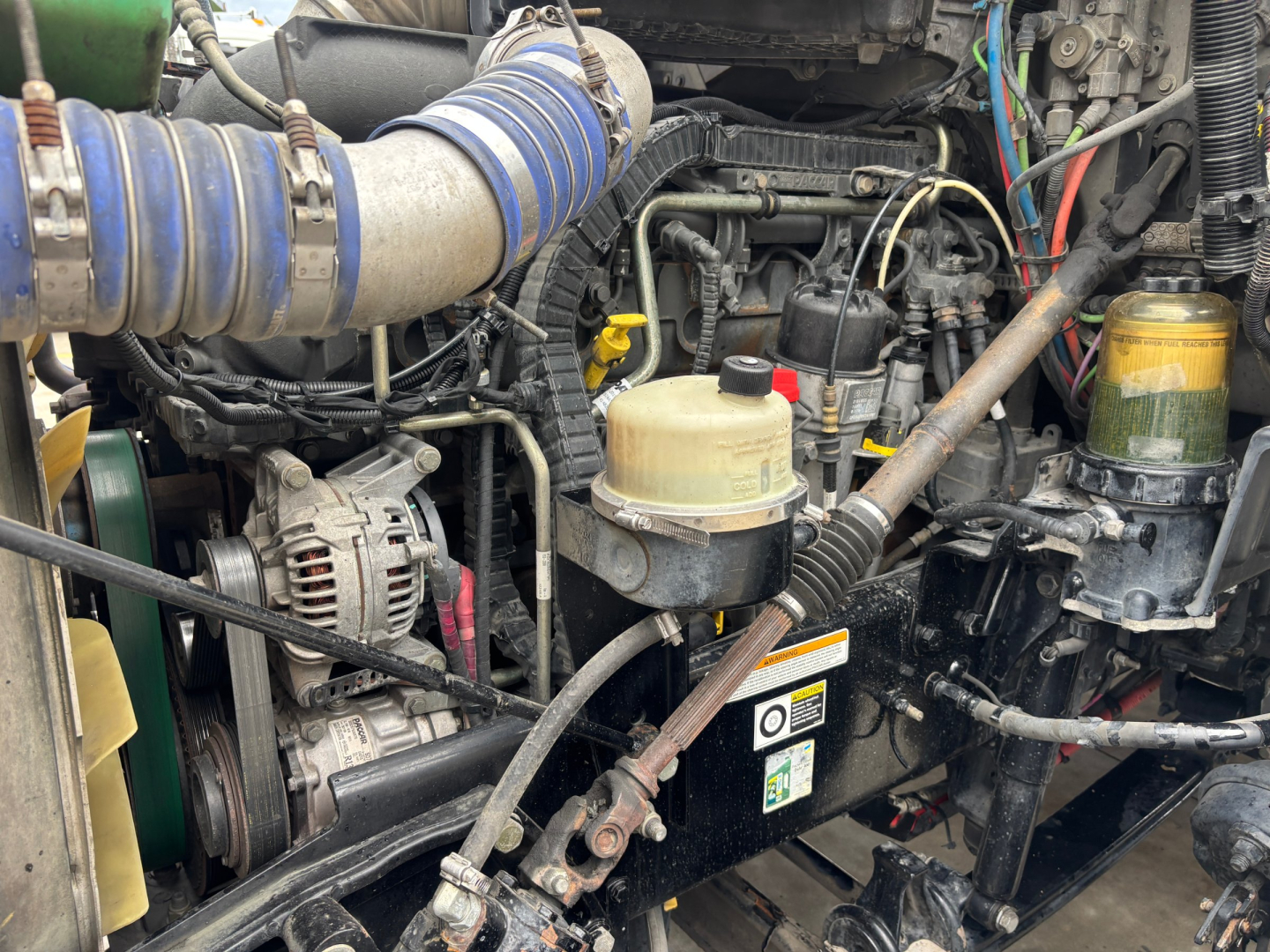Peterbilt 579 engine bay with hoses, belts, and fluid reservoir visible in a used truck.