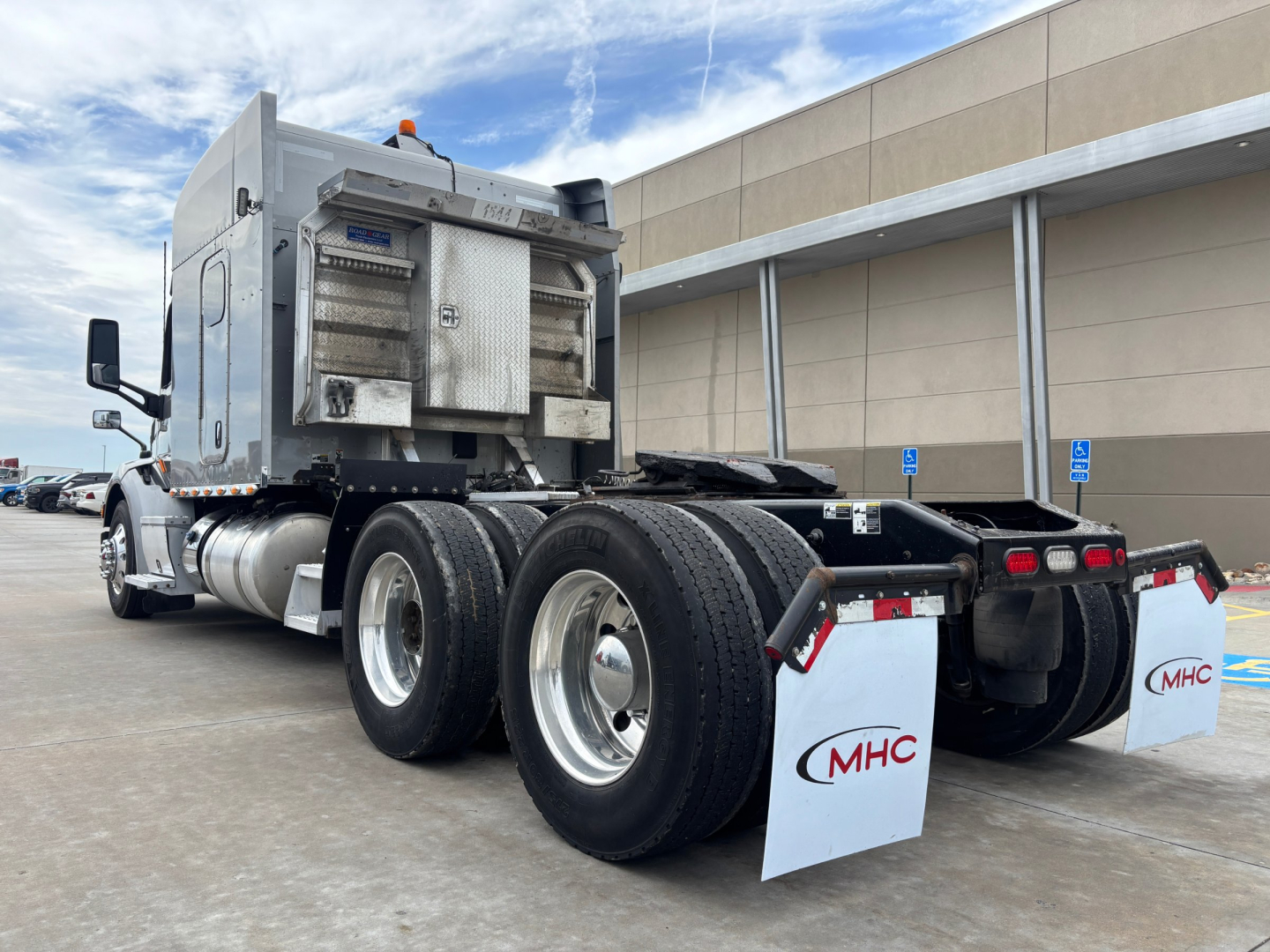 Peterbilt 579 truck rear view showing dual rear axles with mud flaps and chrome fuel tanks; sleeper cab with external exhaust; no license plate visible.
