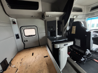 Interior of a 2020 Peterbilt 579 truck cab showing side console with storage and seating area.