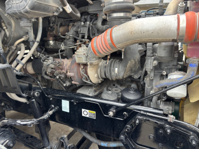 Peterbilt 579 engine bay view showing turbocharger, intake tubing, and various hoses in a conventional sleeper truck.