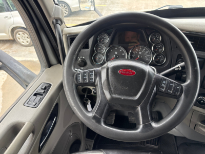 Peterbilt 579 interior view showing steering wheel with Peterbilt emblem and instrument cluster; dashboard controls visible