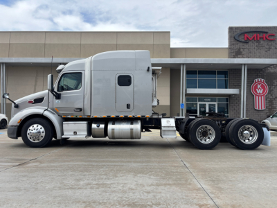 Peterbilt 579 tractor in side view showing sleeper cab, fuel tanks, and fifth wheel with triple rear axles.