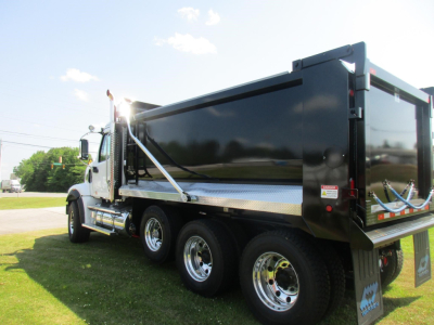 Dump truck side and rear showing Western Star 49X dump bed, dual rear axles, chrome wheels, and black dump body with reflective diamond plate accents.
