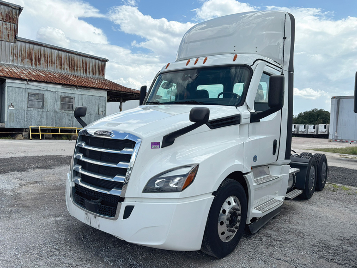 Freightliner Cascadia 126 tractor cab in white, side view showing aerodynamic mirrors, windshield, and chrome grille. VIN label and decals not legible from distance.