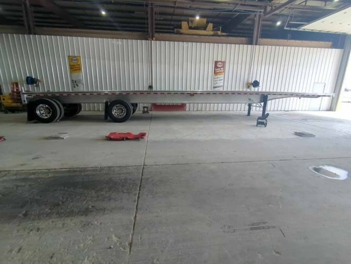 Flatbed trailer in warehouse showing long aluminum deck with dual rear axles and front nose riding wheel assembly. 150119312058 stock number 92593.