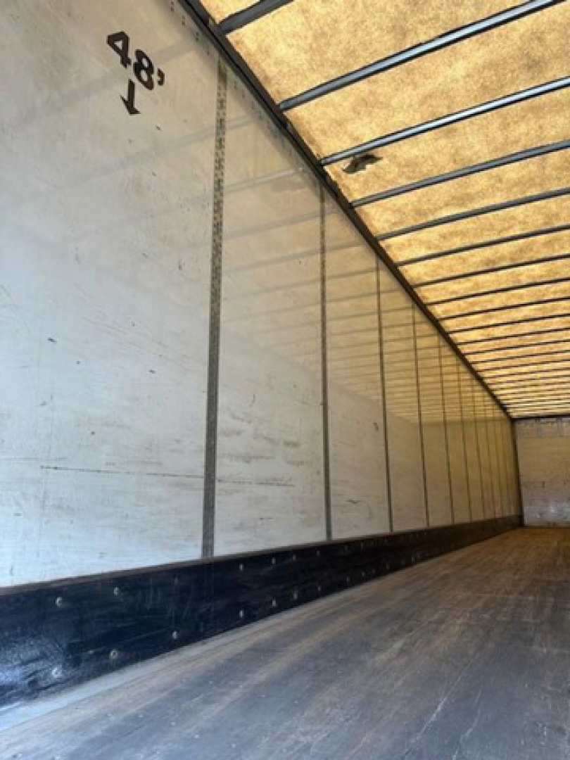 Van trailer interior showing aluminum side walls with 4'8" height marking and ribbed ceiling.