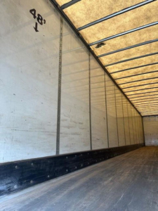 Van trailer interior showing aluminum side walls with 4'8" height marking and ribbed ceiling.