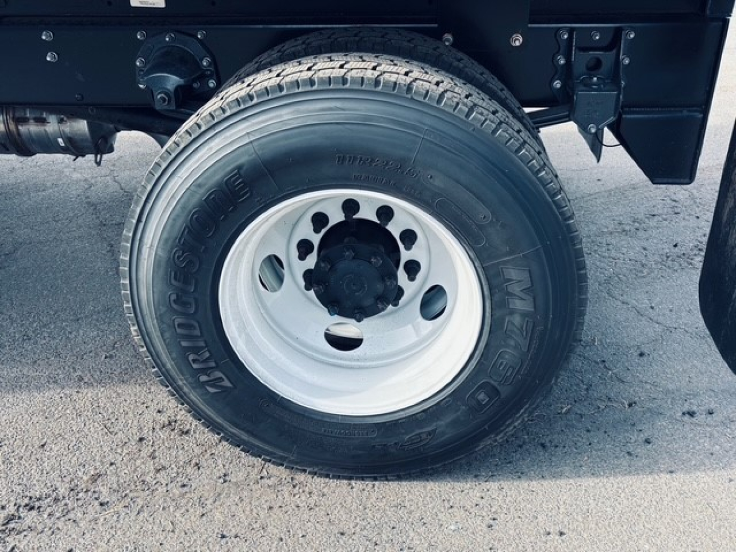 Wheel and tire of a 2025 Mack MD6 dump truck showing Bridgestone tire and white steel rim.