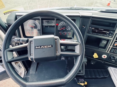 Mack MD6 cab interior showing steering wheel with MAEK logo, instrument cluster, dashboard controls, and radio/display panel.