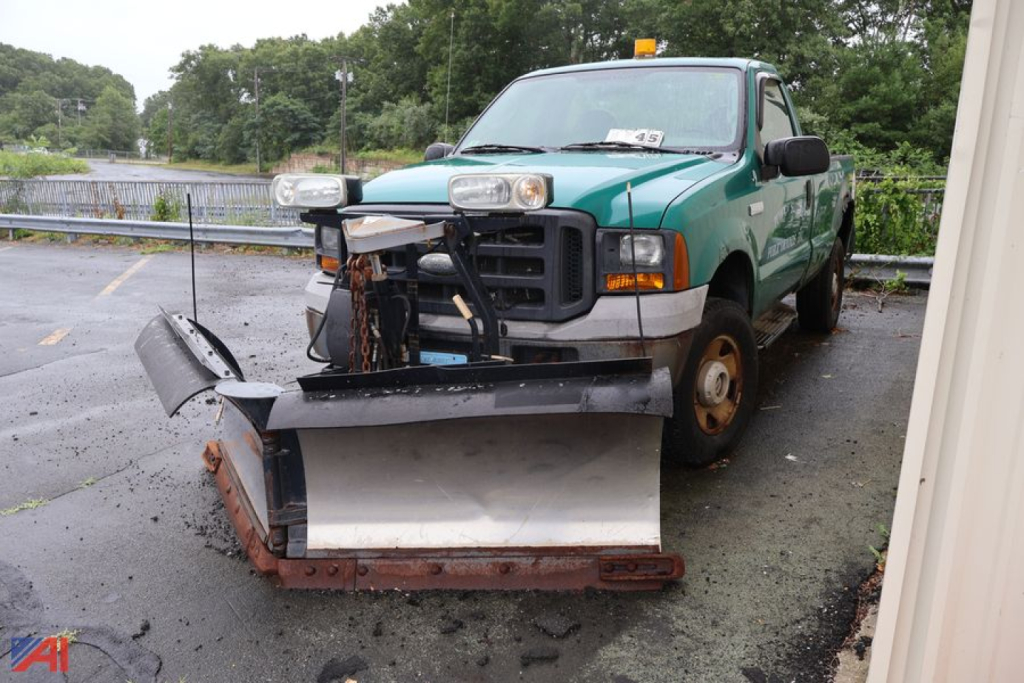 Ford F-250 Super Duty pickup truck with snow plow attachment front view showing green body and black plow blade.
