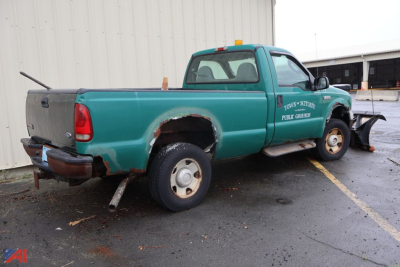 2005 Ford F-250 Super Duty pickup with plow attachment, green body, rust on wheel well, visible rear bumper damaged, running boards, dual rear wheels.
