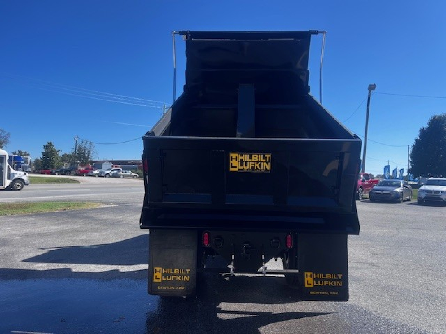 Rear view of a black dump truck bed showing Hilbilt/Lufkin branding on mud flaps and tailgate.