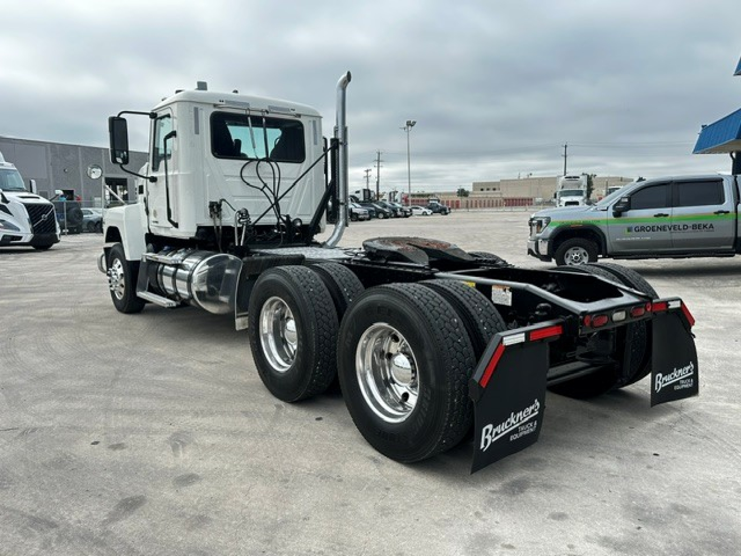 Truck chassis with cab and dual rear axles showing Mack PI64T model, rear wheels, fifth wheel, fuel tanks, and mudflaps with Brundt wheels branding.