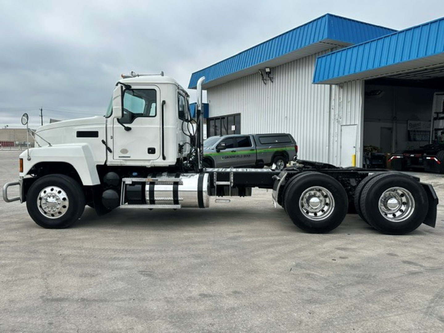 Mack PI64T conventional daycab truck side view showing front cab, chassis, and dual rear axles with chrome fuel tanks.