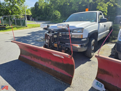 Chevrolet Silverado 2500HD pickup with snow plow blades attached, front view, 4x4, white crew cab, plow mounting hardware visible.