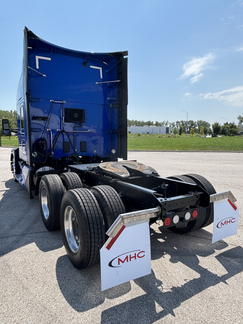 Kenworth T680 tractor rear view showing fifth wheel, dual rear axles, and mud flaps with MHC logos.
