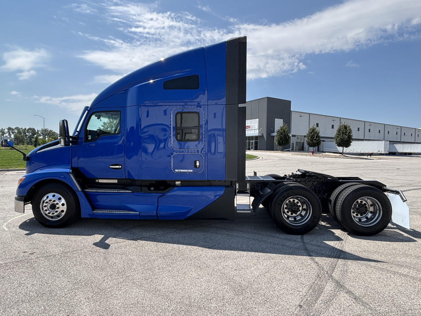Blue Kenworth T680 semi tractor side view showing sleeper cab with black aerodynamic fairing and dual rear axles.