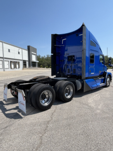 Kenworth T680 tractor in blue, side/rear view showing sleeper cab and dual rear axles with fifth wheel, no visible text on image.