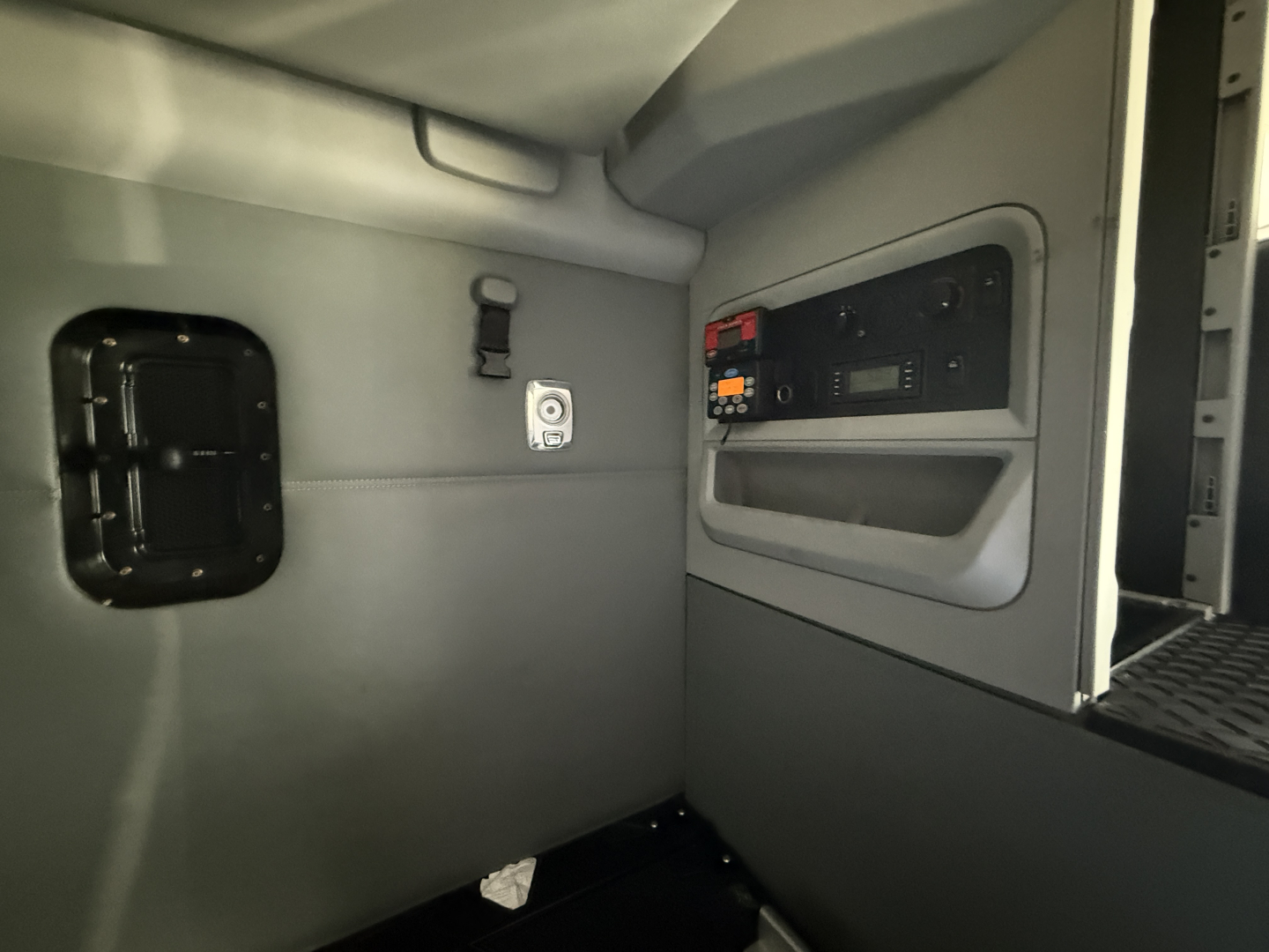 Interior of a used 2021 Kenworth T680 cab area showing side panel with switches, a small window hatch, and a control panel/seat area.