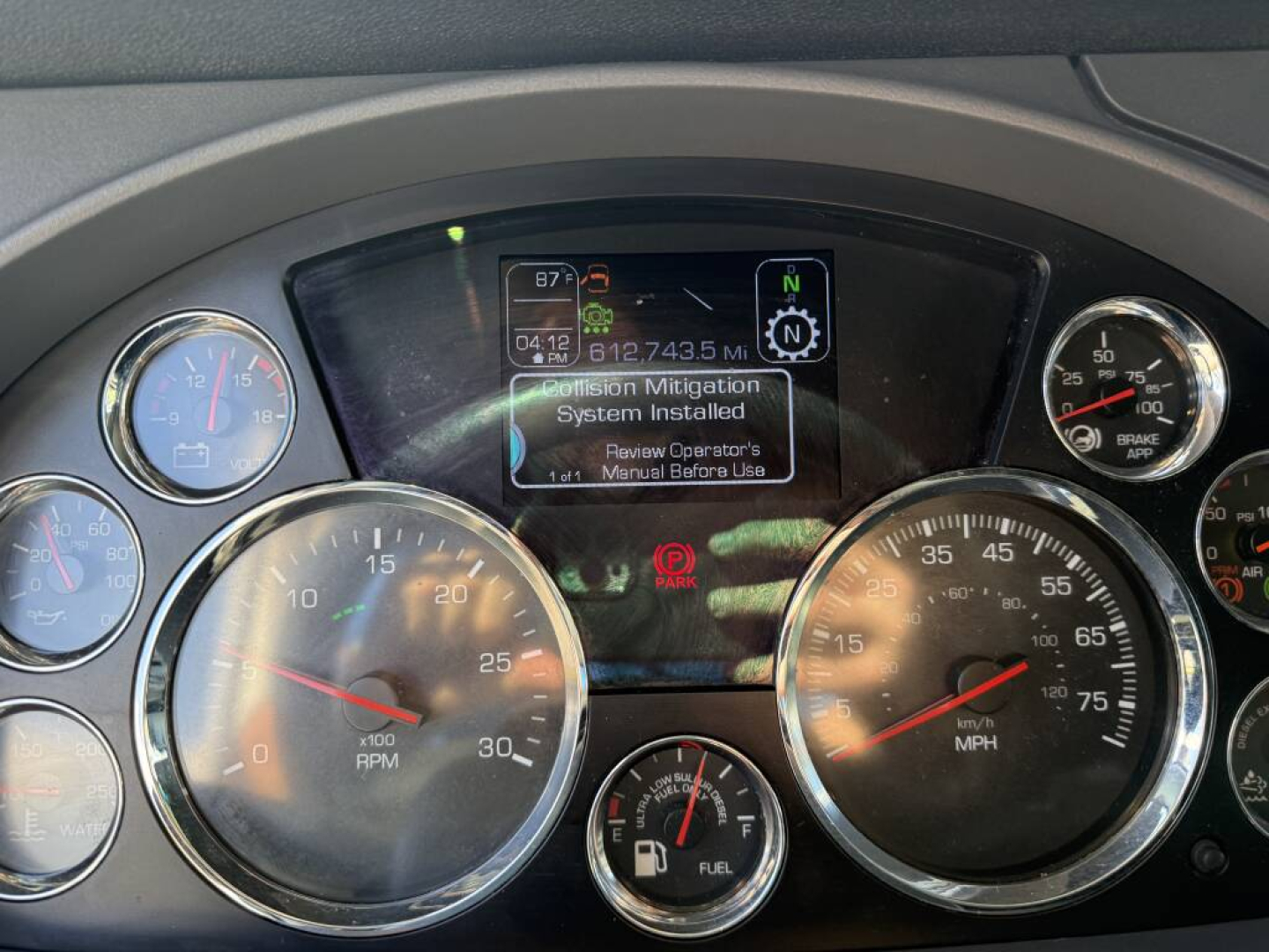 Kenworth T680 dashboard cluster showing analog gauges and a central display with maintenance message
