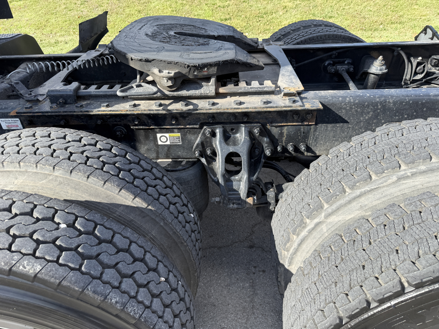 Kenworth T680 chassis showing rear dual axle undercarriage and fifth wheel area, with visible springs, mounts, and tires.
