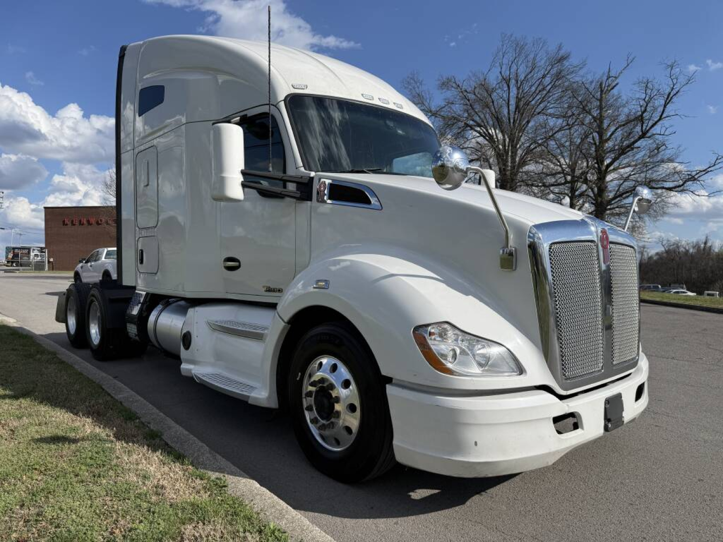 Kenworth T680 conventional sleeper truck in white, front-left angle, showing large grille, aerodynamic cab, dual rear axles, and chrome bumper.