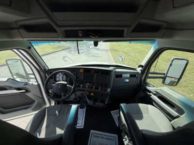 Kenworth T680 cab interior showing steering wheel, dashboard, driver and passenger seats, front windshield and side mirrors.