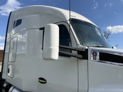Truck cab side view showing Kenworth T680 with large white sleeper, mirror, and wing; no legible labels visible.