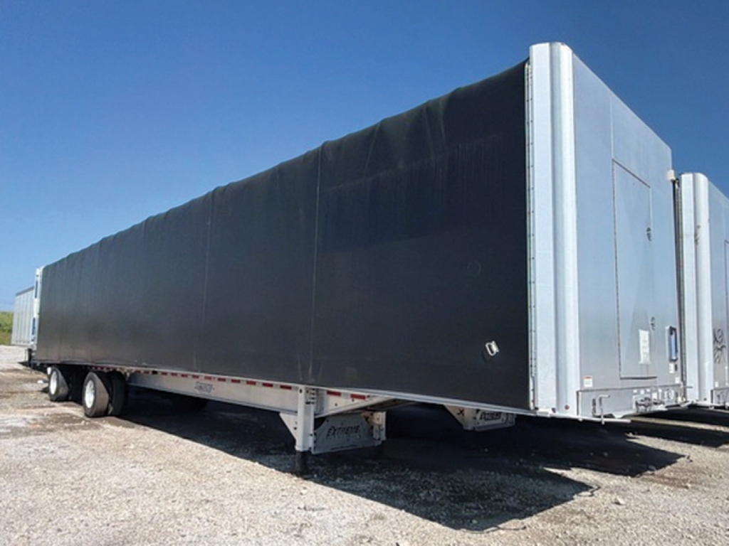 Trailer side view of a 2022 Extreme Aluminum Curtainside Flatbed showing black curtain with silver end caps and dual rear doors.
