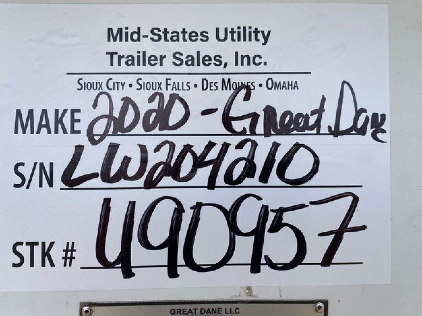 Mid-States Utility Trailer Sales sign with handwritten VIN, S/N, and stock number. Printed header reads 'Mid-States Utility Trailer Sales, Inc.' with locations Sioux City, Sioux Falls, Des Moines, Omaha. Handwritten text includes 'MAKE' fol